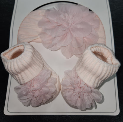 Set of pink baby booties with ruffled tops on a white card.